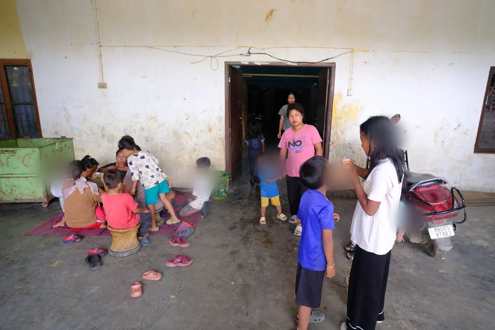 Children gather at the camp gate to meet the camera, their faces blurred for protection, used to being looked at after three years in the camps.