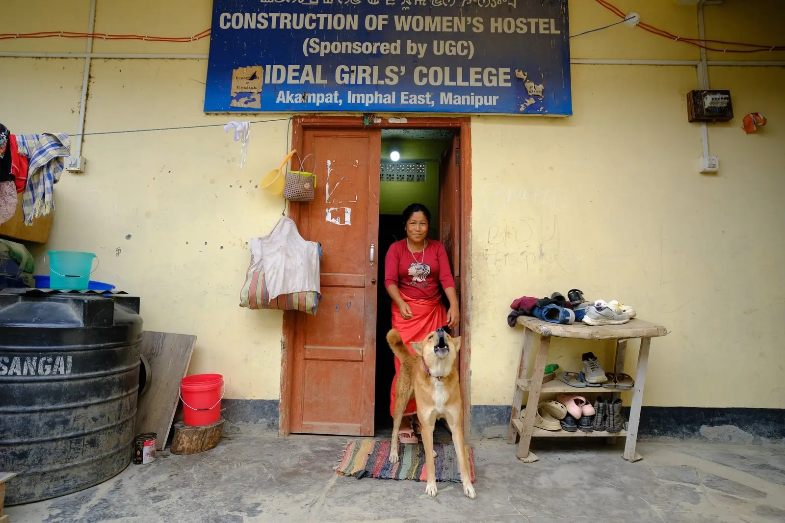 A women's college hostel in Akampat, Imphal East, now used as a relief camp; its old painted signboard still fixed above the entrance, advertising the building it used to be.